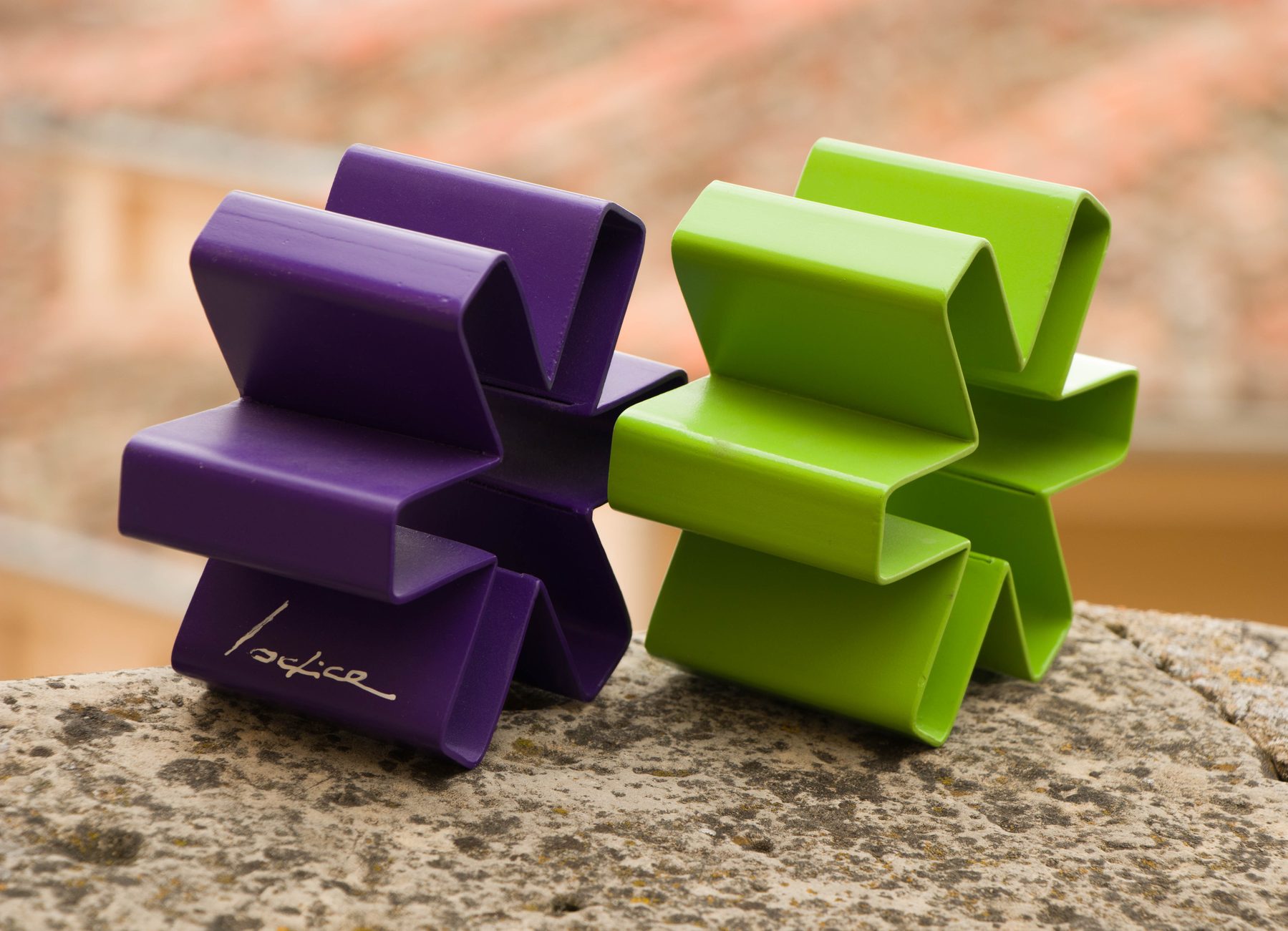 Dos esculturas de asteriscos, en morado y verde, sobre piedra