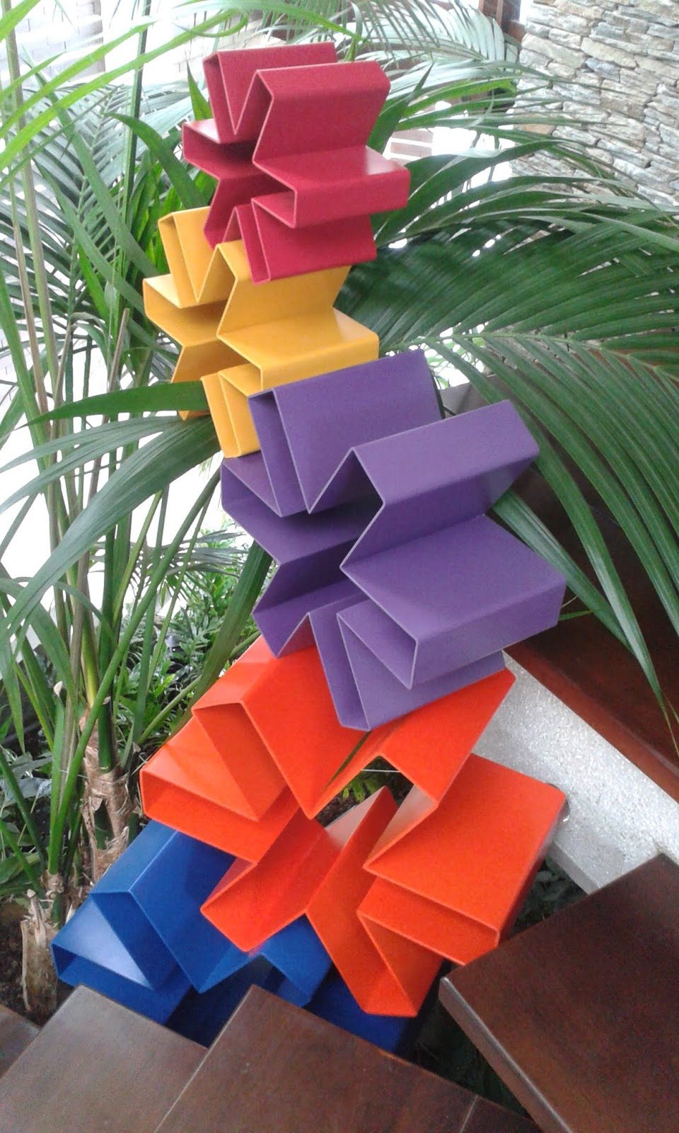 Tótem de esculturas de asteriscos de colores, apilado en un jardín