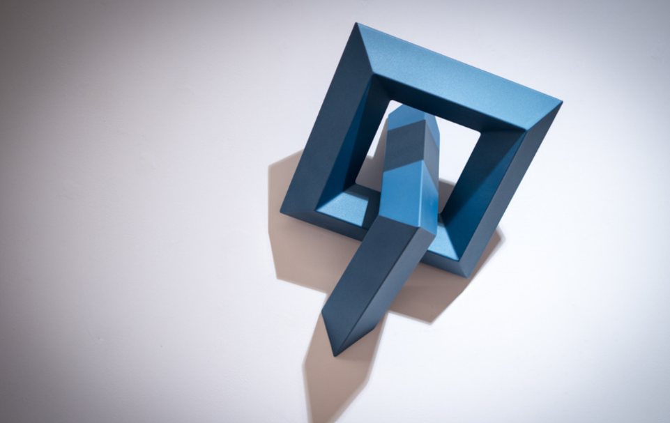 Escultura geométrica azul de formas entrelazadas, sobre fondo blanco