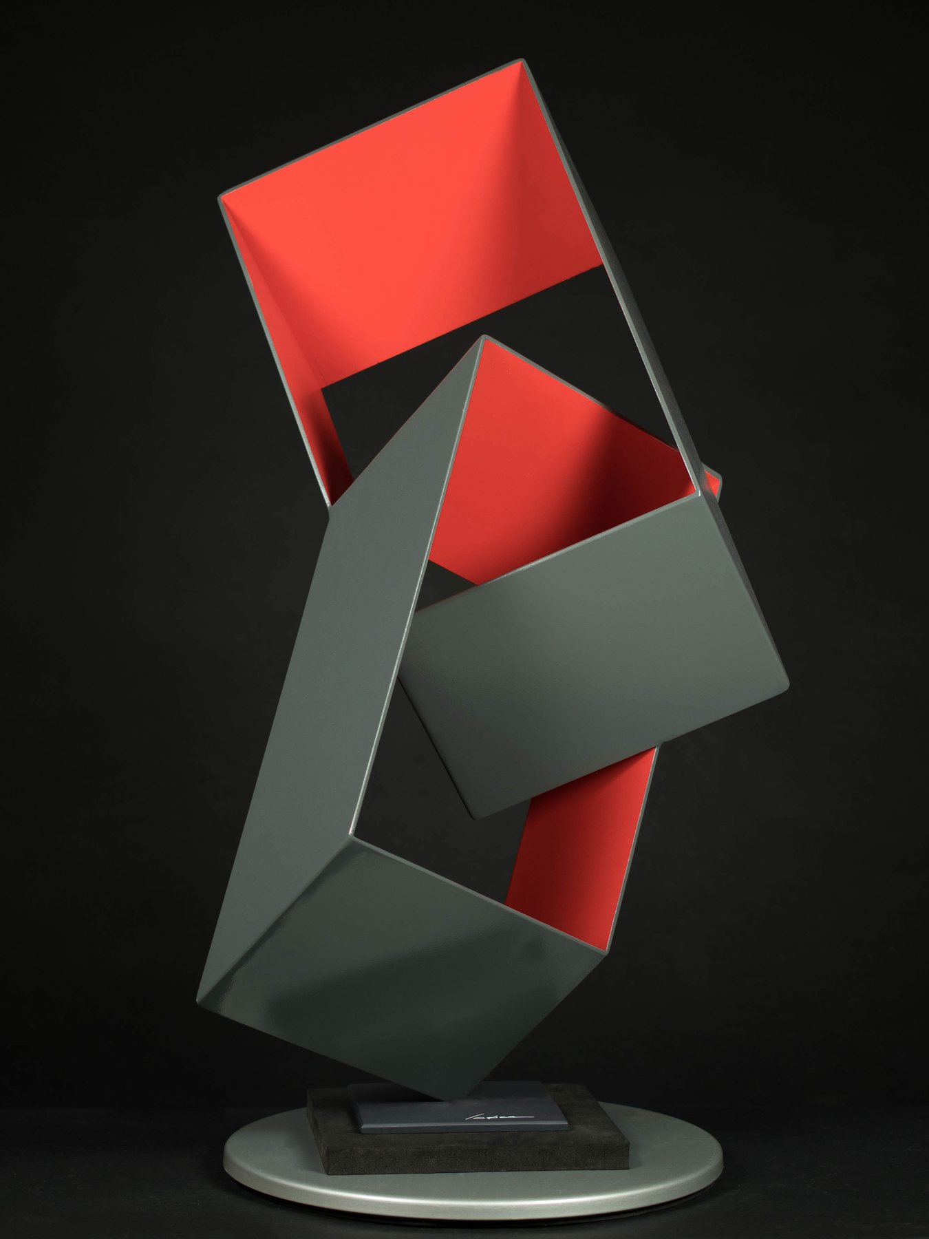 Escultura geométrica en gris y rojo, formas entrelazadas