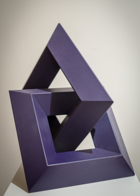 Escultura geométrica triangular en morado, formas entrelazadas