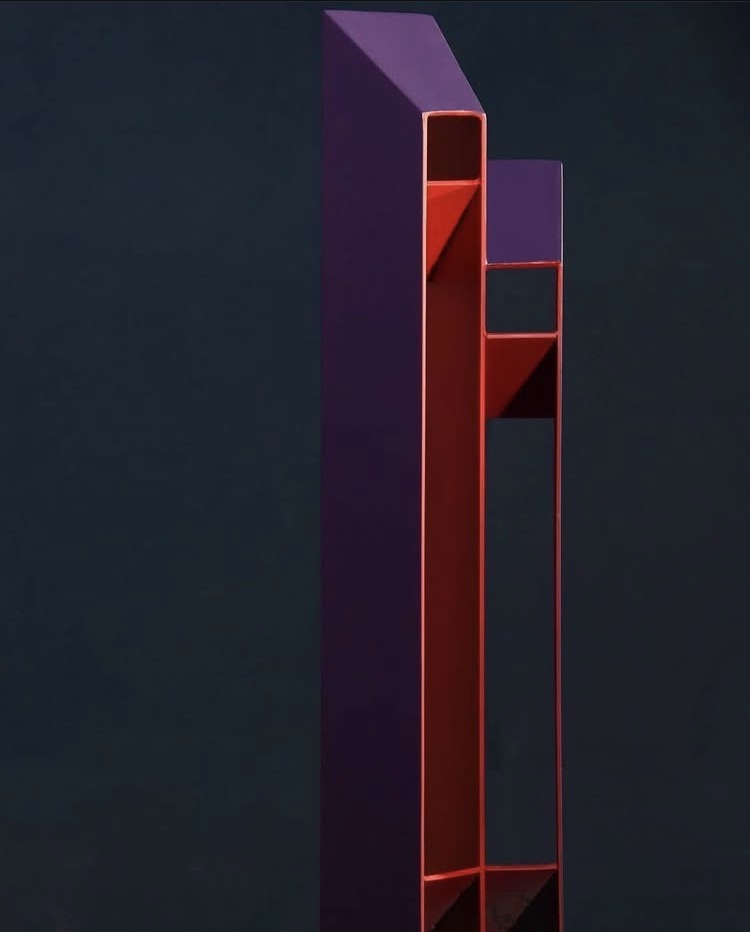 Escultura vertical de la serie Personas, en morado y rojo, sobre fondo oscuro
