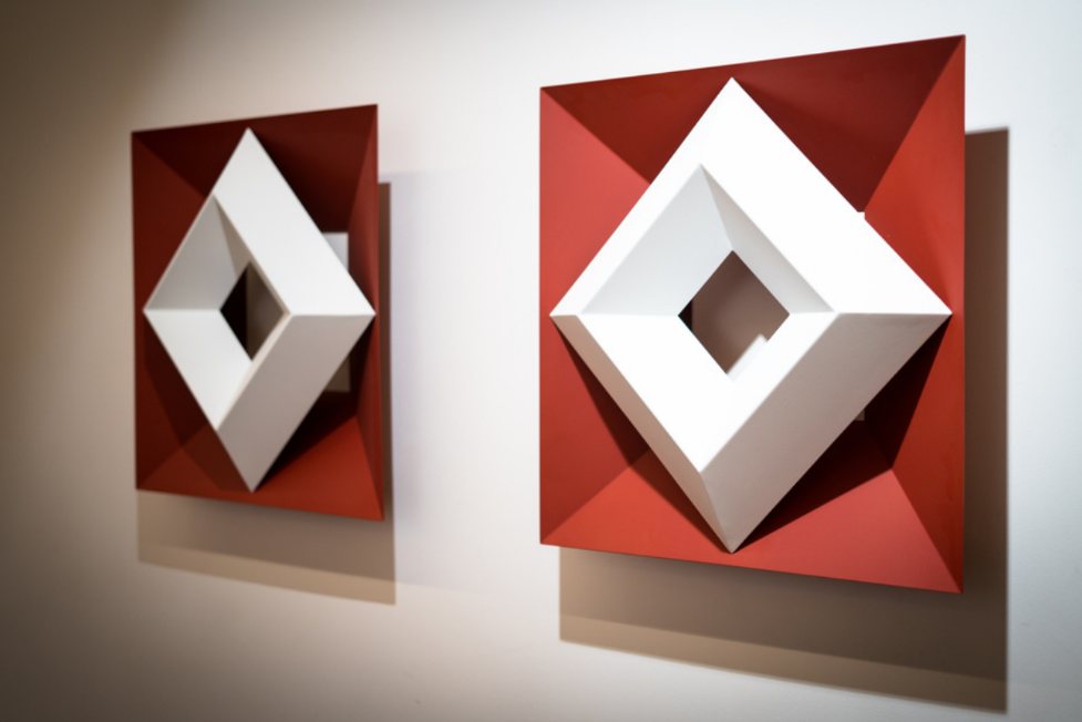 Dos esculturas de marcos geométricos en rojo y blanco, montadas en una pared